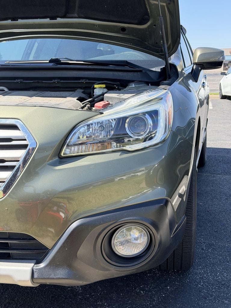 Silver SUV with open hood displaying engine compartment in a parking lot