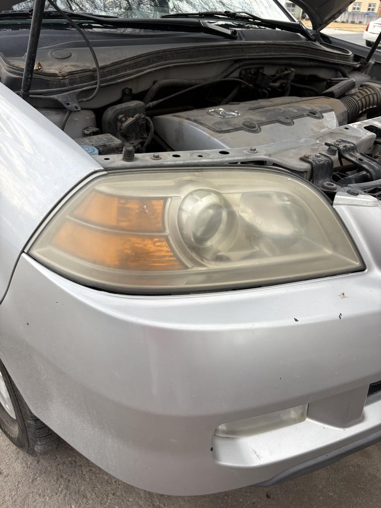 White car with open hood showing engine compartment and hazed headlight with amber section